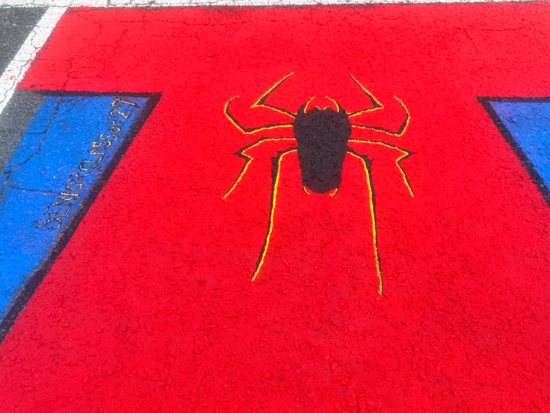 Close-up detail of the painted spider emblem on the red mural surface