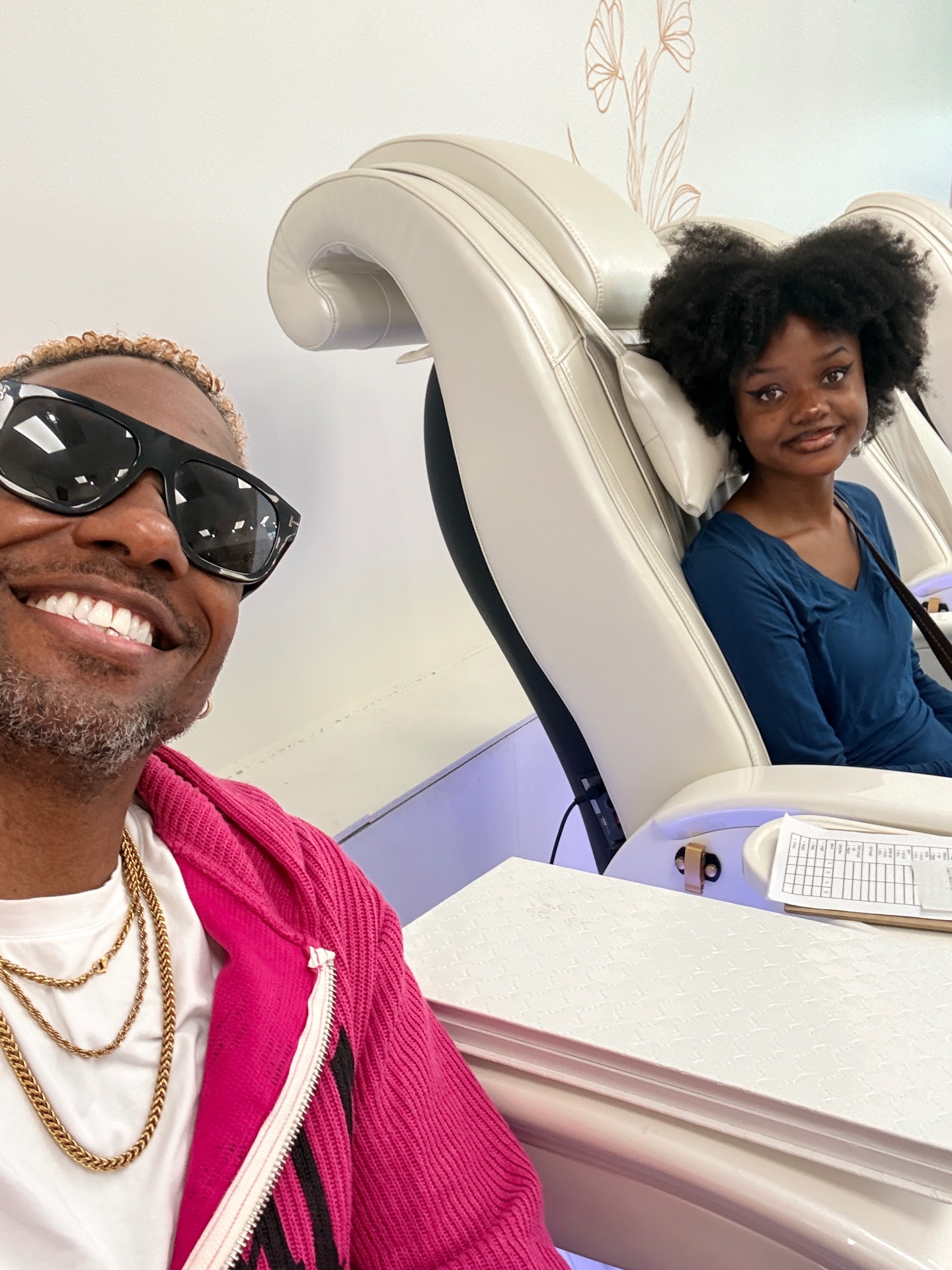 Terry and Anabelle Hammons together in a salon, Anabelle seated in a white massage chair and Terry smiling beside her