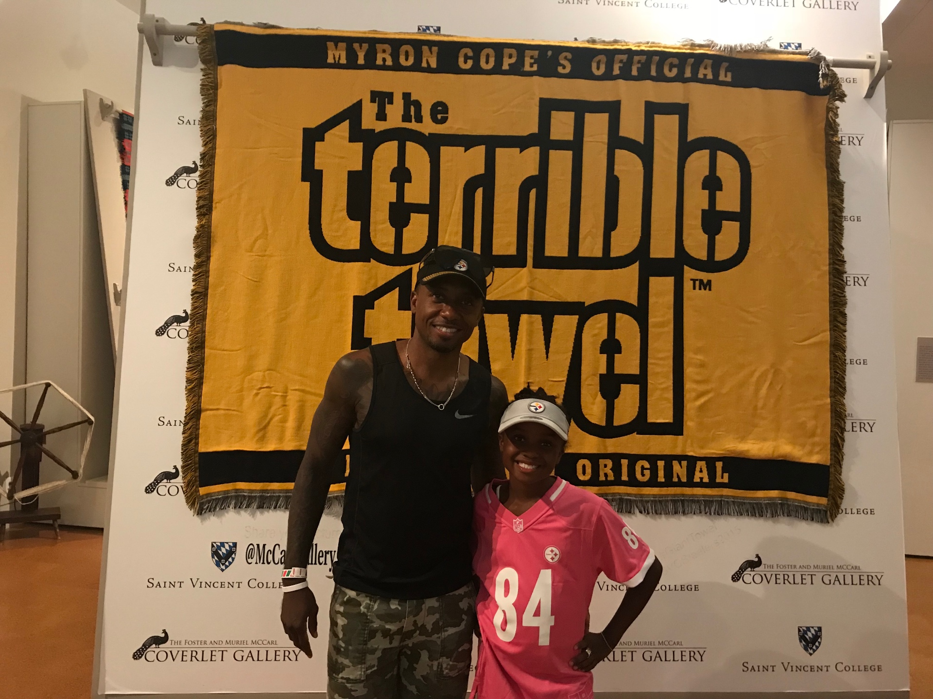 Terry and Anabelle Hammons standing in front of a large yellow Terrible Towel banner